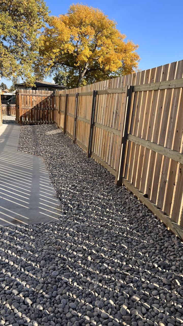 Decorative rock bed beside a backyard fence in Lethbridge